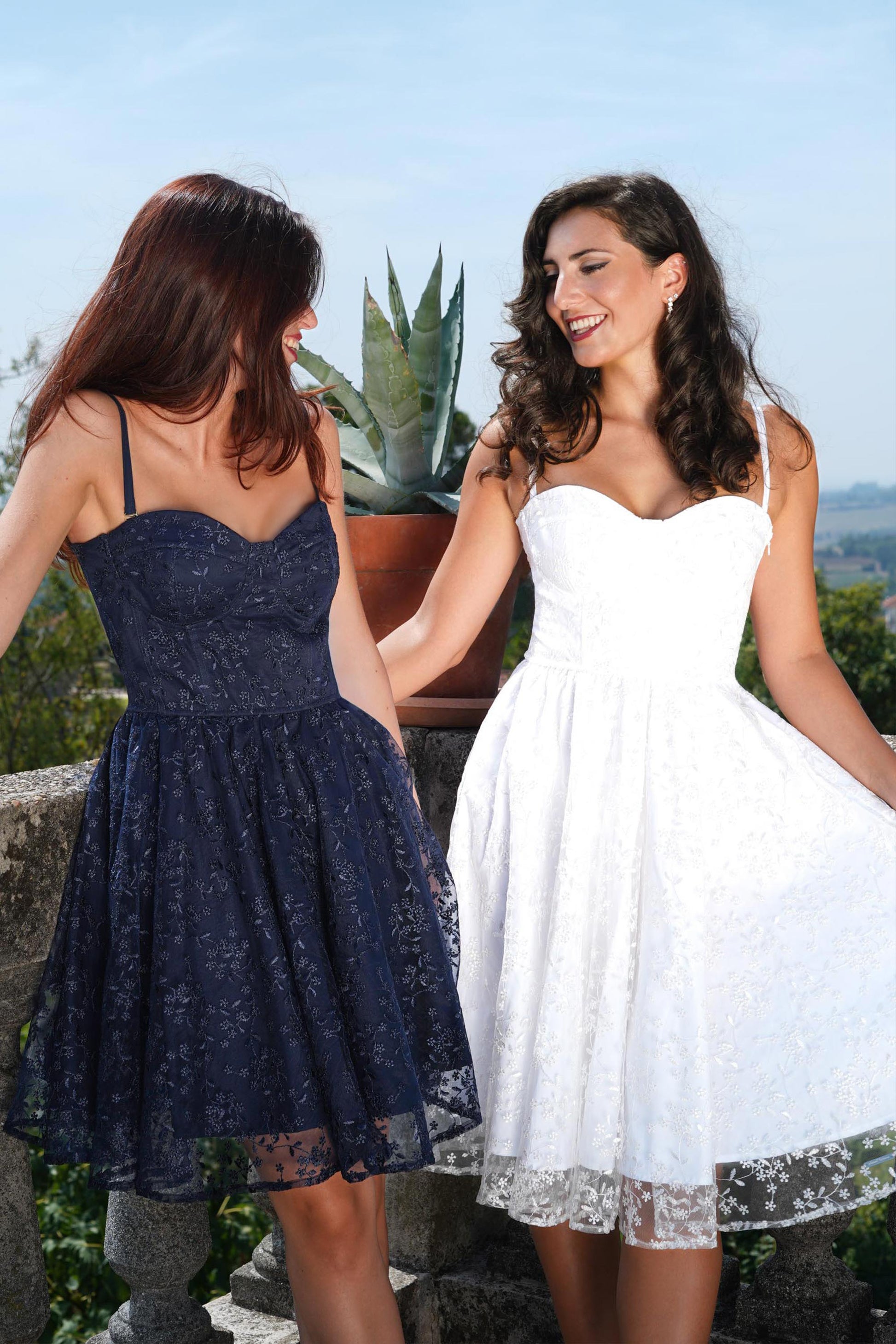 Due abiti midi in tulle ricamato, uno bianco e uno blu notte, indossati all’aperto